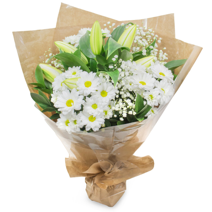 A refined, timeless bouquet in white and green, photographed upright against a neutral white background to emphasise its structure and textures. At the centre, a generous mass of white chrysanthemum blooms creates a comfortably full, rounded silhouette - each bloom composed of many fine petals fanning from a soft yellow centre that lends a cheerful core to the otherwise serene palette. Threaded among the chrysanthemums are long, pale green lily buds; their smooth, tapered shapes and subtle striping are a quiet reminder of unfolding beauty, most remaining closed so the arrangement reads with gentle anticipation. Sprays of delicate baby's breath (Gypsophila) float between the major flowers, their miniature blossoms creating a soft, gauzy veil that adds lightness and breath to the overall form. Deep green foliage provides a rich backdrop and frames the blooms, the leaves' glossy texture balancing the matte softness of petals. The flowers are hand-gathered and wrapped first in rustic brown kraft paper, then protected with a clear, glossy cellophane outer layer that catches the light and preserves the bouquet for transport; the wrapping is neatly tied at the base, creating a stable hand-tied finish. Prepared by the team at Flower Delivery Stanmore, this arrangement reads as both comforting and celebratory - suitable for a quiet anniversary, a new-baby greeting, or a bouquet sent in sympathy - and its understated fragrance is green and clean rather than heady. As a local florist would say when arranging for drop-off near Stanmore Common or for a thoughtful pick-up from Stanmore Broadway, the bouquet communicates care with restrained elegance.