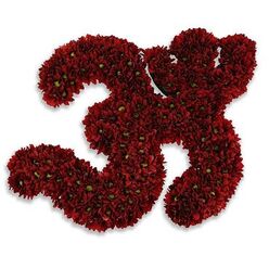 This handcrafted floral emblem gives form to a sacred Om symbol using deep red chrysanthemum blooms, each petal packed with careful intent. Viewed slowly, the symbol's flowing curves are composed of hundreds of small, velvety flowers in a saturated garnet-red, their layered petals creating a plush, tactile surface that suggests warmth and shelter. Many of the tiny blooms reveal a bright green eye at their centres, a delicate counterpoint that livens the composition and emphasizes the organic rhythm of each swirl. The stark white backdrop isolates the Om, making its silhouette confident and calm, while a soft, diffused gray shadow beneath suggests it rests slightly above the plane - a quiet, hovering presence. As a florist in Stanmore who often crafts tributes for moments of reflection near Canons Park or quiet services by Stanmore Broadway, I register this piece as more than ornament: its colour carries the gravity of mourning and the warmth of devotion, its texture offering comfort. Close to the blooms you might imagine a faint, earthy chrysanthemum scent that steadies the spirit and grounds the symbol in living presence. This arrangement balances disciplined structure with unforced beauty, making it suitable as an offering in grief, a focus for meditative ceremonies, or a reverent centrepiece that holds space for remembrance and gentle healing among neighbours and congregations in the local community.