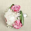 Laid gently on a light beige, linen-textured cloth, this refined bouquet is captured from a slightly raised angle so that every detail of the design can be appreciated. In the centre is a sumptuous creamy white peony, its many layered petals curling and overlapping to form a voluminous, cushiony bloom that evokes the softness of a bridal gown before a ceremony in Stanmore. Framing this focal flower are two striking pink roses, one leaning just above and one slightly below, each rose displaying a perfect spiral of petals that deepen from a gentle pastel pink to a richer magenta tone at their edges. Delicate sprigs of gypsophila, or baby's breath, are nestled between the larger blooms, their fine stems and tiny white flowers creating a misty, ethereal texture, as light and airy as morning fog settling over the lawns of Canons Park. At the base, broad dark green leaves wrap smoothly around the stems, creating a glossy cradle that provides structure and a bold contrast to the softness of the petals. The stems are neatly gathered and encased in a band of white satin ribbon, tied with the precision of an experienced florist preparing bridal flowers for a Stanmore synagogue wedding or an elegant celebration near Stanmore Broadway. The overall impression is one of quiet luxury and heartfelt romance, enhanced by gentle, even lighting that reveals every fold of the petals and the subtle sheen of the foliage. It is a bouquet that would feel perfectly at home in wedding photographs or arriving as a same-day delivery to a loved one in the Stanmore area.
