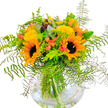 There is a radiant joy in this bouquet-crafted to capture the essence of Stanmore's sunny days and open spaces. Bold sunflowers with golden petals and deep, chocolate centers anchor the arrangement, projecting positivity and vitality familiar to anyone who's admired local gardens along Marsh Lane. Floating nearby are yellow solidago or mimosa, tiny clouds of sunshine threaded through abundant layers of fresh greenery. Coral-orange tulip buds, nestled within, conjure a playful wink of color, introducing a gentle, modern twist among the traditional blooms. Cascading fern fronds, delicate and textured, frame the bouquet with grace, while eucalyptus sprigs and lime-green foliage provide cool, invigorating highlights. As daylight glimmers on the clear glass vase, each submerged stem is revealed, reflecting a sense of purity and contemporary style. This floral arrangement radiates as a lively centerpiece for birthdays, anniversaries, or even a spontaneous gesture of kindness-infusing every Stanmore home with warmth, artistic flair, and the inimitable freshness of the area's beloved parks. Every blossom and leaf tells the story of local care, celebrating joyful connections in and around Stanmore.