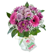 A joyful display of seasonal blooms shines brightly against a white backdrop, its vivid pinks and purples celebrating the floral richness of Stanmore. Cheerful Gerbera daisies in vibrant fuchsia take prominence, their wide petals and bold, midnight centers radiating fun and positivity-ideal for lifting spirits on a birthday morning near Stanmore's Canons Park. Soft lavender roses cushion them, their tender, curling petals exuding gentle fragrance and quiet beauty. Sprays of deep magenta chrysanthemums, rich in color and texture, spill through the arrangement, interlaced with wisps of delicate baby's breath and hints of natural greenery. Gathered in a rounded, clear glass vase with a distinctive crackled pattern, the bouquet is finished with a twine-tied white tag-perfect for sharing heartfelt notes or best wishes. Balanced between elegance and joy, this bouquet offers a fresh, artisan-crafted floral gift, suitable for anniversaries, celebrations, or sending a thoughtful thank-you to anyone in the Stanmore area.
