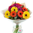 A joyful bouquet of freshly cut Gerbera daisies, hand-tied by Stanmore's expert florists, is beautifully set against a luminous white background in this image. Bursting with vivid yellows, brilliant oranges, and sumptuous magenta blooms, the daisies' dark, expressive centres provide elegant contrast and highlight their radiant petals. The arrangement is laced with leafy greenery, creating natural depth and echoing the lush outskirts of Stanmore Common. Carefully wrapped first in rustic kraft paper, then in a sleek cone of clear cellophane that glimmers under soft light, the bouquet exudes both comfort and sophistication. The stems are visible through the contours of a clear glass vase, submerged in fresh water-a quiet testament to just-picked quality. Binding the stems is a simple twine bow, from which suspends a delicate white tag illustrated with a deep red rose and partially inscribed words-a signature of thoughtful, local gifting traditions. This hand-crafted Gerbera bouquet is perfect for marking special moments-a birthday surprise, an anniversary along The Broadway, or simply a heartfelt thinking of you gesture. The image's attention to detail, warmth, and local authenticity makes it especially suited for Stanmore flower delivery guides, celebratory gift features, or any content highlighting the uplifting spirit of expertly arranged flowers in the Stanmore community.