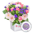A vibrant, celebratory floral arrangement sits proudly in a pristine white square presentation box, a pristine canvas that lets the blooms glow. Within, soft pink roses unfold from tight buds to generous, open blossoms, their classic romance warmed by the gentle glow of surrounding pastel pink gerbera daisies, each edged in crisp white with pale yellow centers that flash like tiny suns. Interspersed among them are clusters of vivid purple filler flowers, likely statice or limonium, adding striking depth and a whisper of drama to the bouquet's cheerful palette. Lush green foliage peeks through in varying shades and leaf shapes, providing a fresh, natural backdrop that makes every petal feel radiant and alive. The box itself is simple and modern, with a front-facing, stylised red rose icon beside green script-an understated branding touch that signals quality and care. Partially visible in the bottom right is a round, shiny foil balloon, the focal point for the occasion. Its surface bears the celebratory message You're Engaged! in bold silver lettering, anchored by a central purple circle and accented by a distinct golden 'O' in You're, a playful twist that adds glamour. The outer white rim is sprinkled with tiny hearts in pink, blue, purple, and grey, with subtle silver stars to evoke joy and romance. This image captures a thoughtful, premium engagement gift-perfect for congratulating a newly engaged couple-with a sense of warmth, celebration, and new beginnings, delivered with care across Stanmore by Flower Delivery Stanmore.