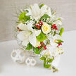 This image shows a richly detailed floral centerpiece, composed in a palette of white, green, yellow, and touches of red, resting on a pristine white tabletop against a warm beige textured background that mirrors the understated elegance of many Stanmore interiors. Dominating the heart of the design are white Oriental lilies, their generous petals fully opened and softly curving outward, revealing delicate speckles and bold stamens that lend a natural, sculptural quality. Near them, a single yellow rose, tightly coiled and buttery in tone, brings a gentle glow that feels like late afternoon light over Stanmore Common. Around these focal blooms float clusters of white baby's breath, tiny blossoms forming soft clouds that blur edges and bring a romantic softness to the arrangement. Spherical tufts of bright green dianthus, reminiscent of moss balls or manicured garden shrubs, add a vivid, tactile contrast, while fine, feathery greenery fills in the gaps, giving the bouquet an airy, organic feel. Here and there, polished red hypericum berries catch the eye, their glossy skins offering lively pops of colour that suggest festive toasts or joyful family gatherings. Flowing from the right, a cascade of white Phalaenopsis orchids spills down in elegant arcs, the flowers' satin-smooth petals and subtle yellow centres adding a refined, contemporary touch suited to modern Stanmore weddings. Fresh green orchid buds and spiky accents stretch the line of the cascade, hinting at blooms still to come and the promise of new beginnings. All of these elements are arranged in a white woven basket base, its texture mirrored by two white wicker spheres placed thoughtfully to the left on the table, completing a scene of harmonious design and quiet celebration.