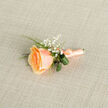 This intimate buttonhole is a study in gentle contrast and careful construction: a single apricot-peach rose forms the focal point, its centre tightly furled and the outer petals opening in graduated tones from deep honeyed apricot to a creamy blush. Surrounding it, tiny white gypsophila blossoms skim the air like confetti, lending an airy, romantic halo that lifts the composition. Slim, bright green grass blades and two darker curled leaves are tucked discreetly behind the bloom, their satin sheen and folded shapes creating a subtle rhythm and botanical interest against the rose's soft curves. The stems are wrapped with a coordinating peach satin ribbon, tied into a neat bow whose smooth texture reflects the same warm light that plays across the petals; a small metallic pin is visible near the base, indicating it has been finished for attachment to a lapel. The boutonniere lies on a lightly textured beige linen background-its cross-weave softens reflections and provides a neutral, tactile backdrop that accentuates the floral colours. I imagine this worn at an intimate Stanmore wedding near the tube station or pinned on a father's jacket at a ceremony held by the Common: it feels grounded and unpretentious, fragrant with rose-sweetness and the green, clean scent of fresh foliage. As a local floral designer, I see this as versatile and quietly celebratory-perfect for spring and summer formals or thoughtful gift-giving to mark tender beginnings in the neighbourhood.
