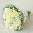 Softly luminous against a textured neutral backdrop, this bouquet embodies the elegant serenity treasured in Stanmore's community. The creamy white roses-each a gentle promise in bloom-are surrounded by mist-like clusters of baby's breath, creating a tactile harmony that mirrors the tranquillity of Church Road or afternoons spent in Canons Park. Sprays of slender bear grass arch in contemporary loops through the arrangement, their lively green a vibrant counterpoint to the creamy florals. Binding the bouquet is an exquisite band of silver-toned ribbon, intricately studded with lustrous pearls, forming a handle both beautiful to behold and comforting to the touch. Just beneath this wrap, fresh green stems splay slightly, revealing the bouquet's natural vitality. Crafted with loving attention to detail and a deep understanding of Stanmore's refined aesthetic, this arrangement becomes more than a wedding or anniversary accent-it is a memory in bloom, designed to accompany joyful moments and heartfelt milestones throughout the area.