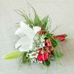 Set delicately atop a light beige fabric reminiscent of the welcoming settings of Stanmore's favourite event venues, this meticulously arranged bouquet brings together the emotional resonance of weddings with the expertise of a local Stanmore florist. A breathtaking white lily, petals gracefully open and patterned with subtle reddish-brown spots at its heart, commands attention at the centre, radiating softness and poise. Next to it, a deep crimson rose in rich bloom spirals towards its core, infusing the arrangement with romantic significance. Interwoven clusters of glossy, bright red berries add lively, festive contrast, while frosty-white baby's breath scatters a gentle haze of brightness, enhancing each flourish. Framing these blossoms, abundant foliage-including feathery ferns and deep green leaves-creates a lush, textured backdrop akin to the gardens and parks for which Stanmore is known. Emerging to one side, a slender lily bud hints at the future, bringing a note of hope to the composition. Each stem is precisely gathered and finished with a lustrous red satin ribbon, echoing the ruby tones and providing classic refinement. Purposeful and composed, this bouquet is ideal for bridesmaids or as a cherished accent for celebrations, capturing the fresh elegance and vibrant community spirit unique to Stanmore.